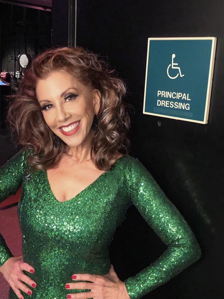 A woman in green dress standing next to a handicap sign.